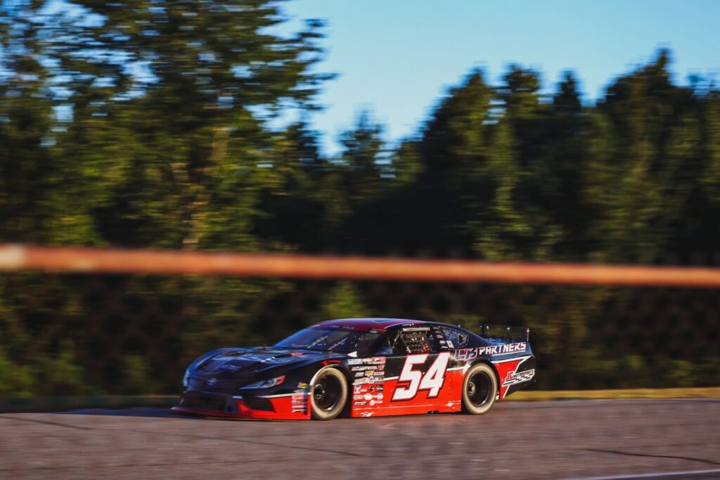 The #54 JC Motorsports Pro Late Model at speed in late-day light